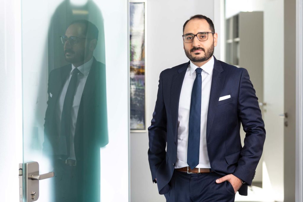 Unternehmensfotografie eines Rechtsanwalts. Das Portrait spiegelt sich in einer Tür.