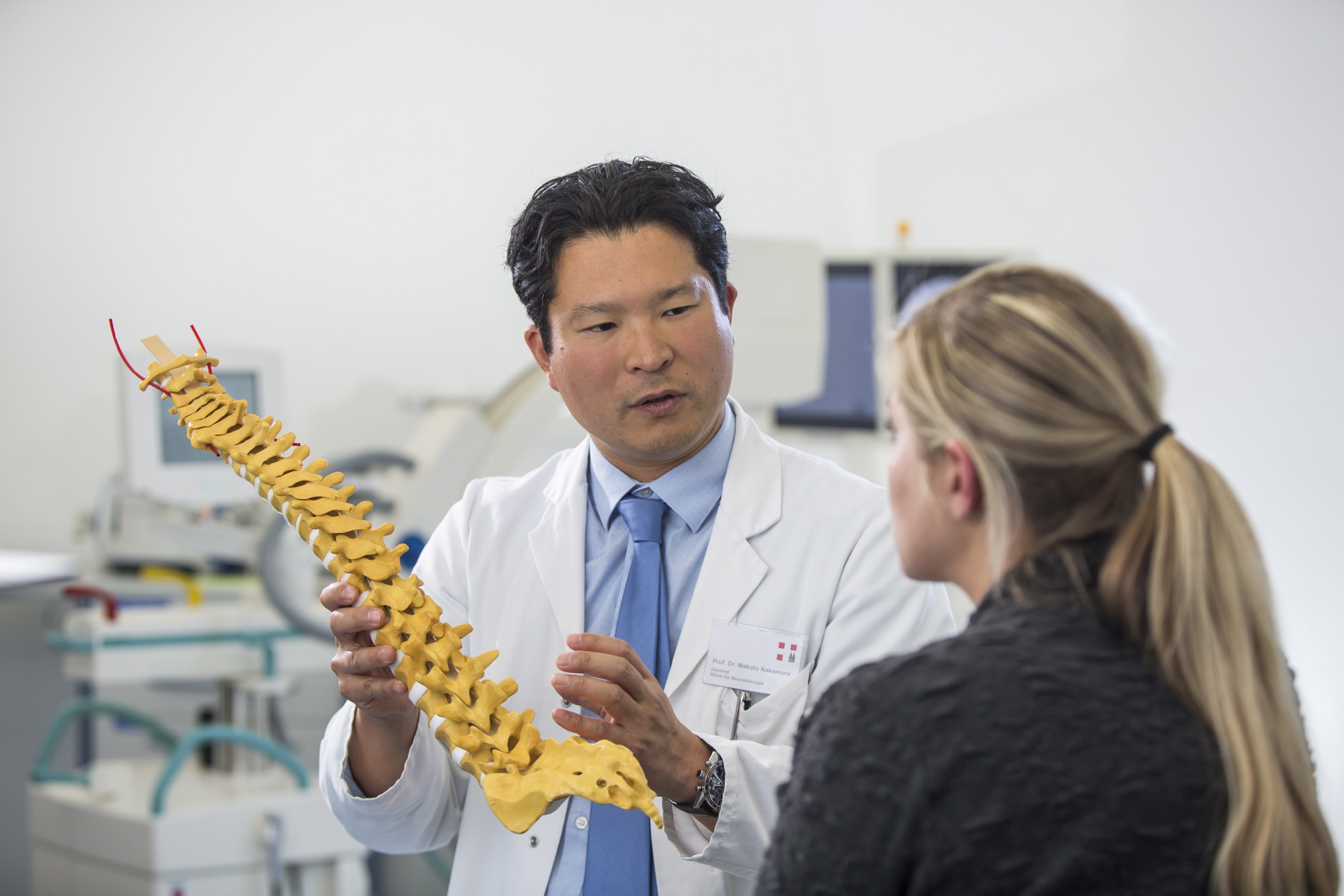 Ein Oberarzt erklärt einer Patientin die Behandlung an der Wirbelsäule