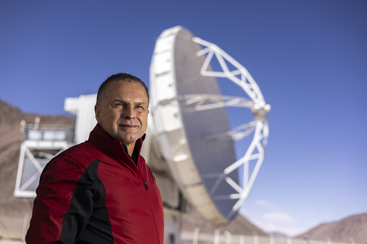 Ein Wissenschaftler steht vor einem Radioteleskop in der Atacama Wüste