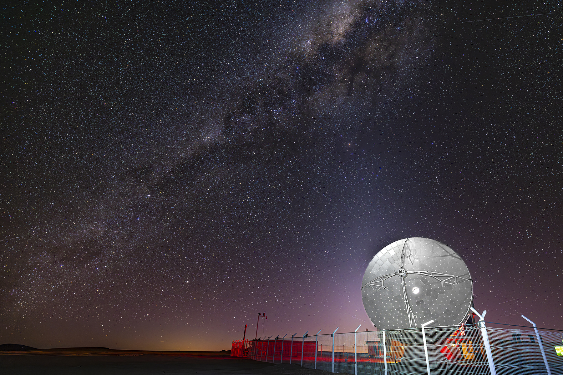 Ein Radioteleskop in Chile bei nacht. Es ist die Milchstraße zu sehen.
