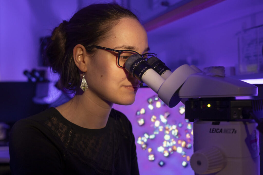 Eine Wissenschaftlerin schaut durch ein Mikroskop