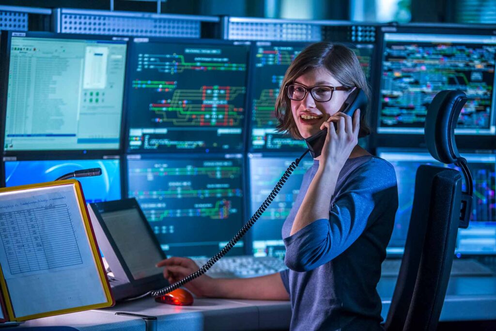 Auszubildende in einer Schaltzentrale mit Telefon am Ohr