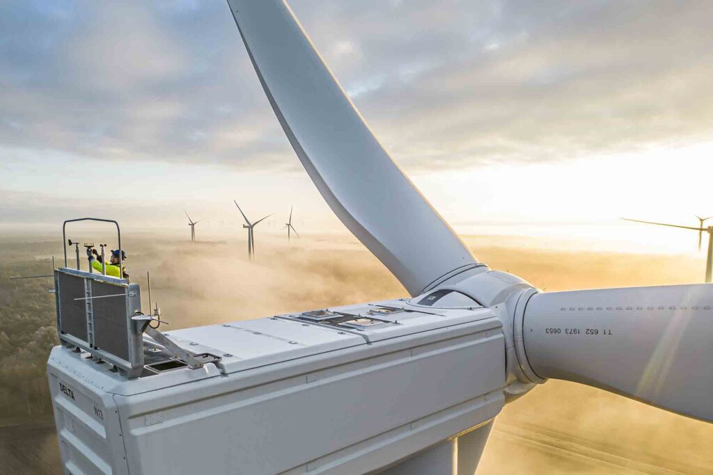 Windpark im Nebel und ein Ingenieur kontrolliert die Windanlage
